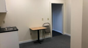 An empty 600 SF office room with a table and a sink available for lease in Allentown.